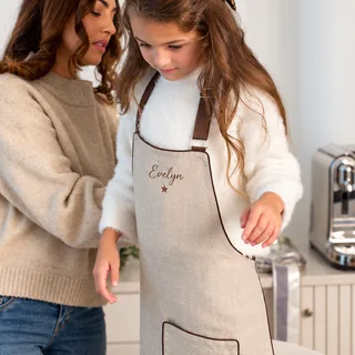 A girl wearing her TSC Christmas apron with her name on it, her mum beside her