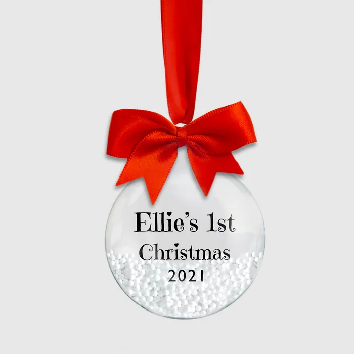 A clear bauble with a red bow printed with Ellie's 1st Christmas 2021