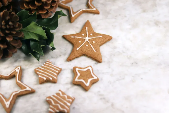 Gingerbread stars piped with thin lines of white icing on a snowy marble surface