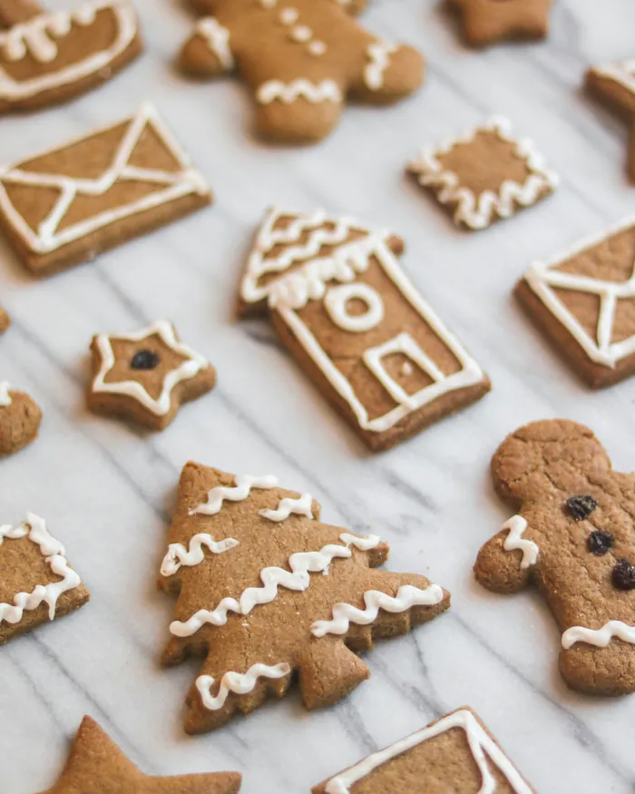 Gingerbread biscuits shaped like little houses, envelopes and trees, outlined in white icing
