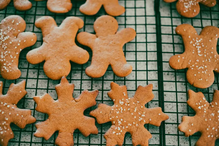Plain gingerbread people and a snowflake cooling on a black wire rack