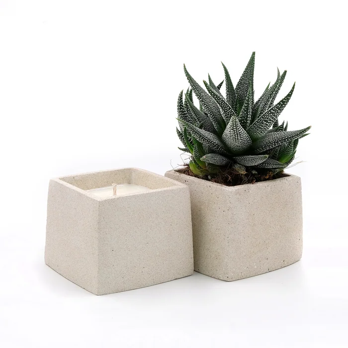 Two square stone pots, one holding a candle and one a succulent