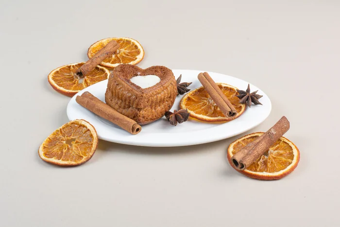 A small candle on a plate with dried orange slices, cinnamon sticks and star anise