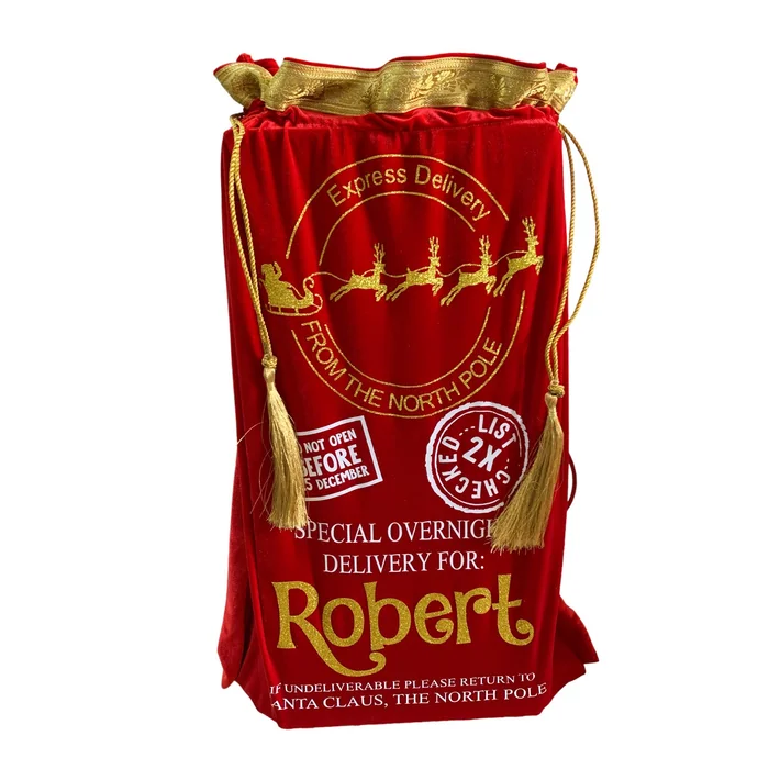 A red velvet Christmas Eve sack with gold tassels, printed with a delivery label for Robert