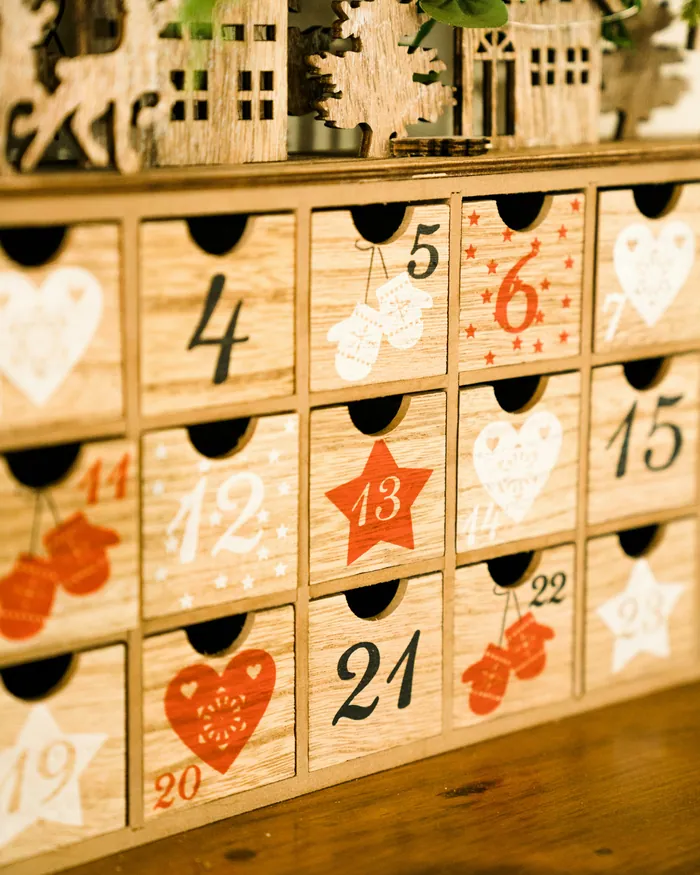 A wooden advent calendar of little numbered drawers painted with hearts and stars