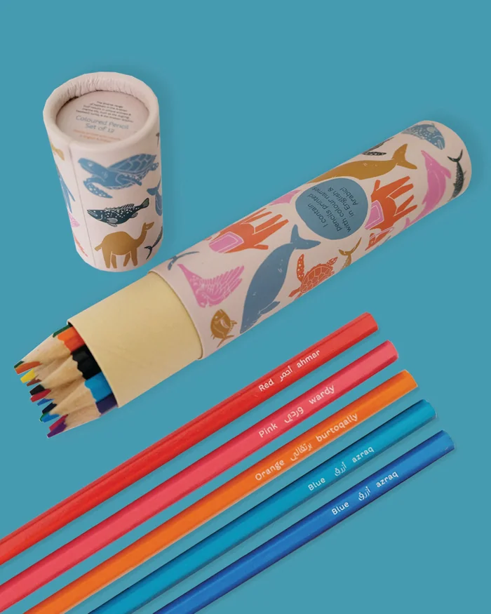 A tube of colouring pencils printed with birds and fish, the pencils fanned out on a blue background