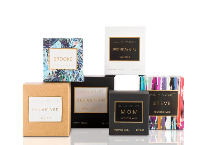 Julia Volet candles in boxes with personalised labels, among them Mom, Steve and Birthday Girl, on a black background