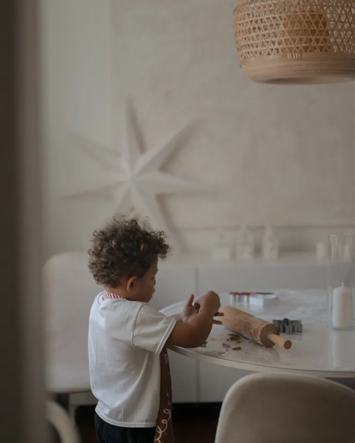 A small boy playing at a white table in a quiet room with a paper star