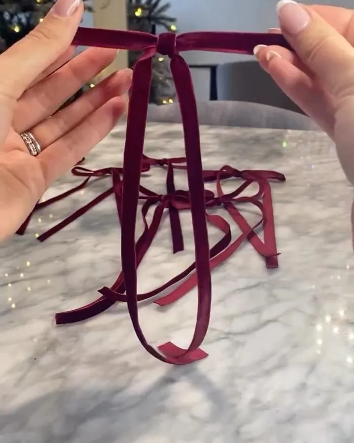 Hands tying a burgundy velvet ribbon into a bow