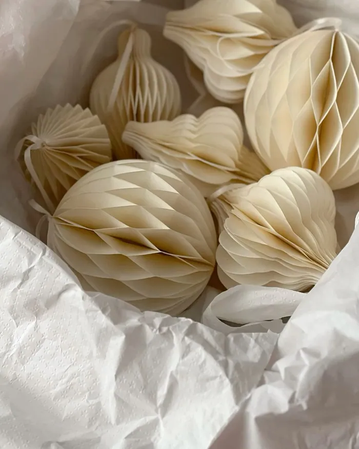 Cream paper honeycomb ornaments nested in white tissue paper