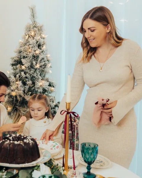 A mother serving a family at a Christmas table with a chocolate bundt cake, a small girl watching