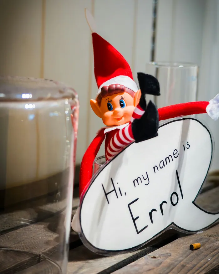 A toy elf leaning out from behind a card that reads Hi, my name is Errol