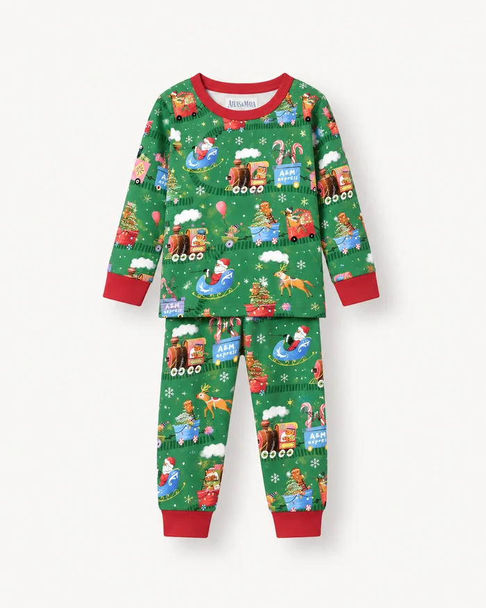 A child's green pyjama set printed with Christmas trains and gifts, with red cuffs