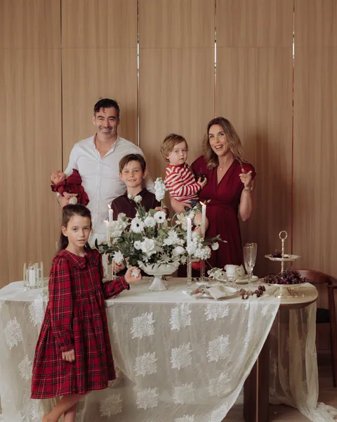 A family of five standing around a lace-covered table set for Christmas tea