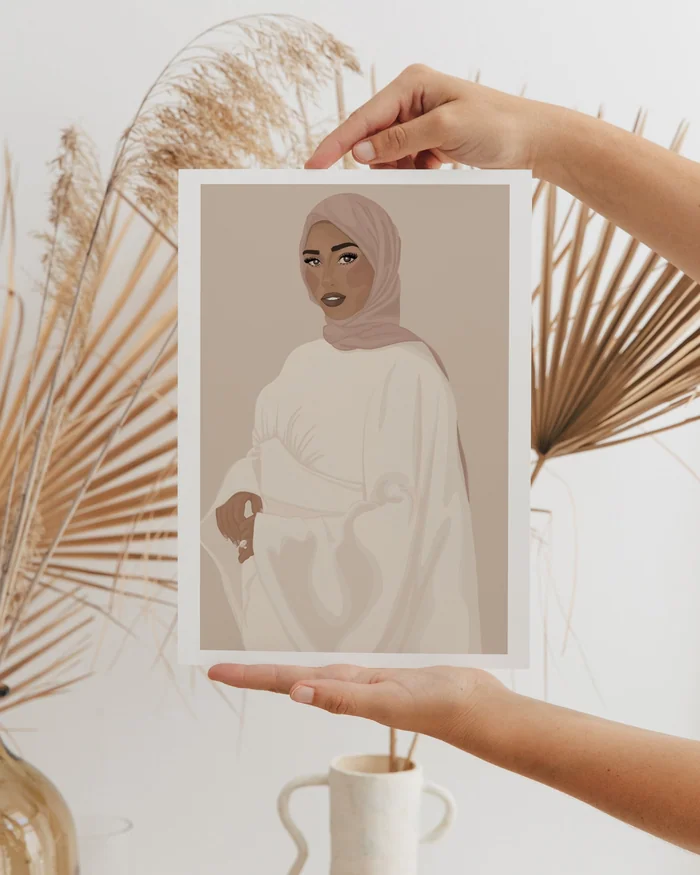 Hands holding a printed illustration of a woman in a headscarf, beside dried palm leaves