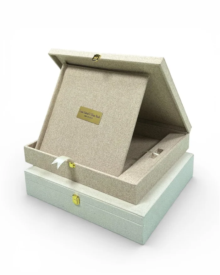 An open linen-covered keepsake box with a small engraved plate on the lid