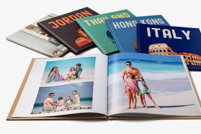 An open photo book of family holiday pictures with travel photo books stacked behind