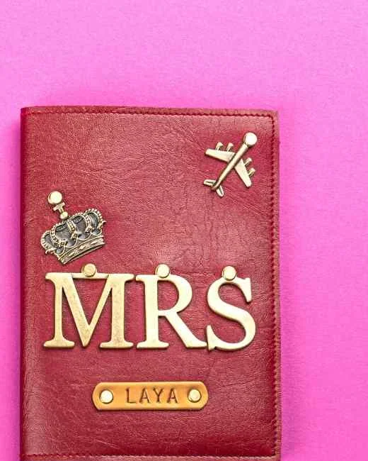 A deep red leather passport cover with MRS in gold letters, a crown and a small gold name tag