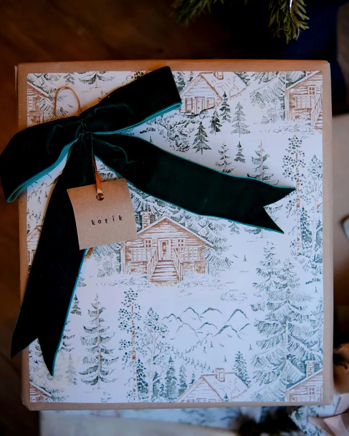 A present in woodland-print paper tied with a dark green velvet bow and a name tag