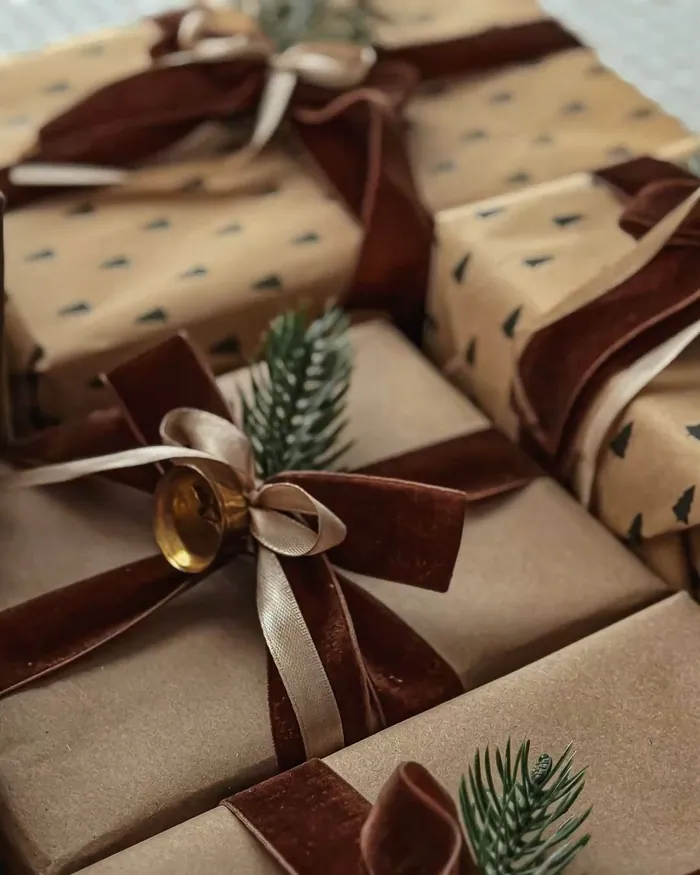 Parcels in brown paper tied with burgundy velvet ribbon and a sprig of fir