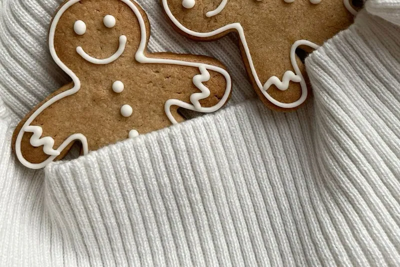 Two iced gingerbread men lying on a cream knitted jumper