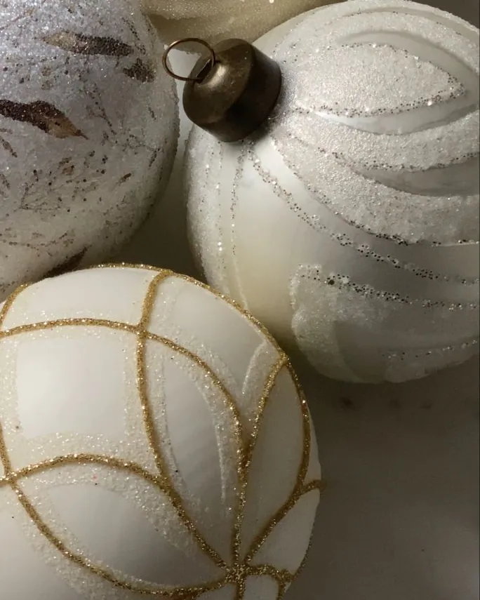 White and cream glass baubles, frosted with glitter and traced in gold