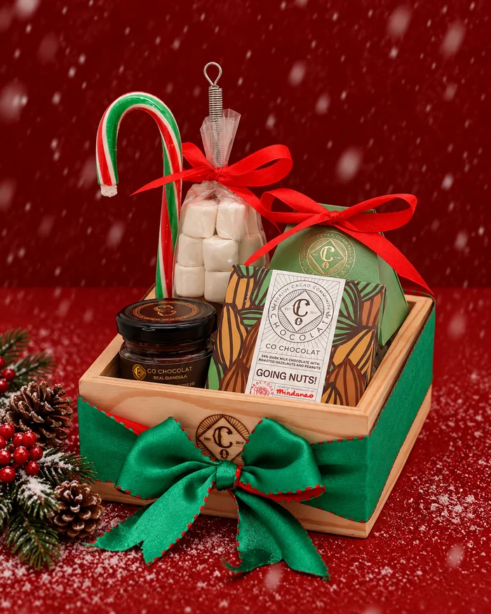 A wooden crate of Christmas treats with a candy cane, a green bow and a chocolate bar