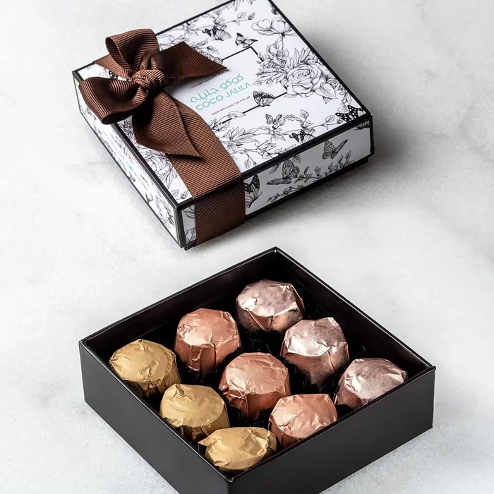 A gift box tied with a brown bow and an open box of foil-wrapped chocolates