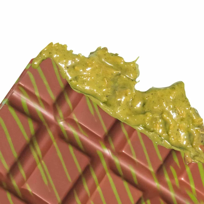 A close view of a chocolate bar topped with green pistachio filling