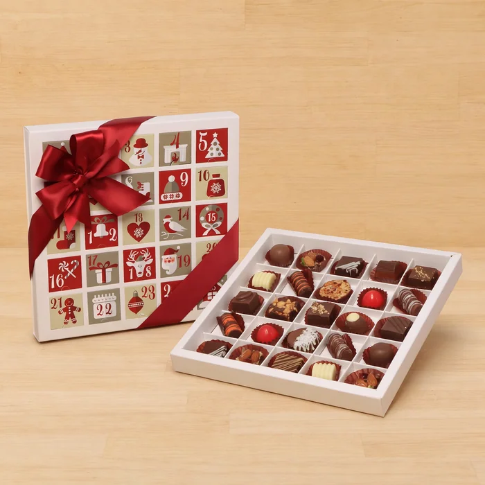 A chocolate advent calendar with a red bow beside an open box of filled chocolates