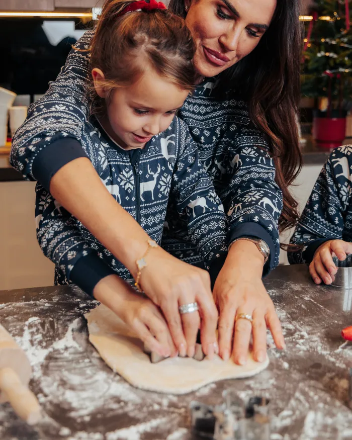 A mother and daughter in matching navy jumpers pressing dough on a floured counter
