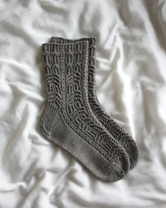 A pair of grey cable-knit wool socks on white linen