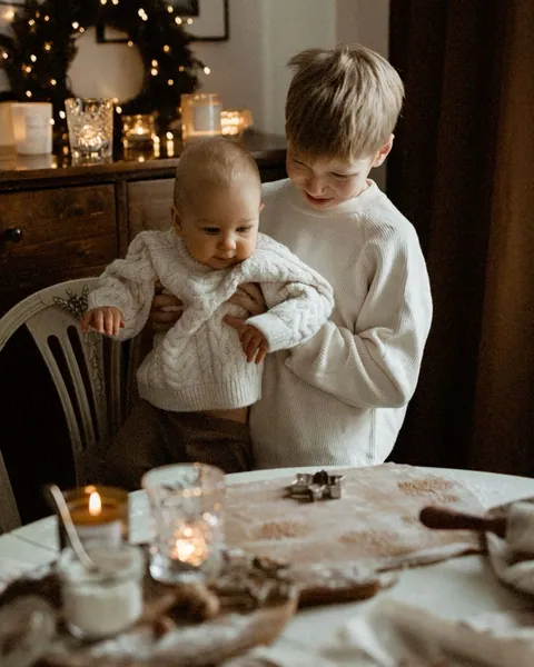 Two young brothers in cream cable knits at a table laid for Christmas baking