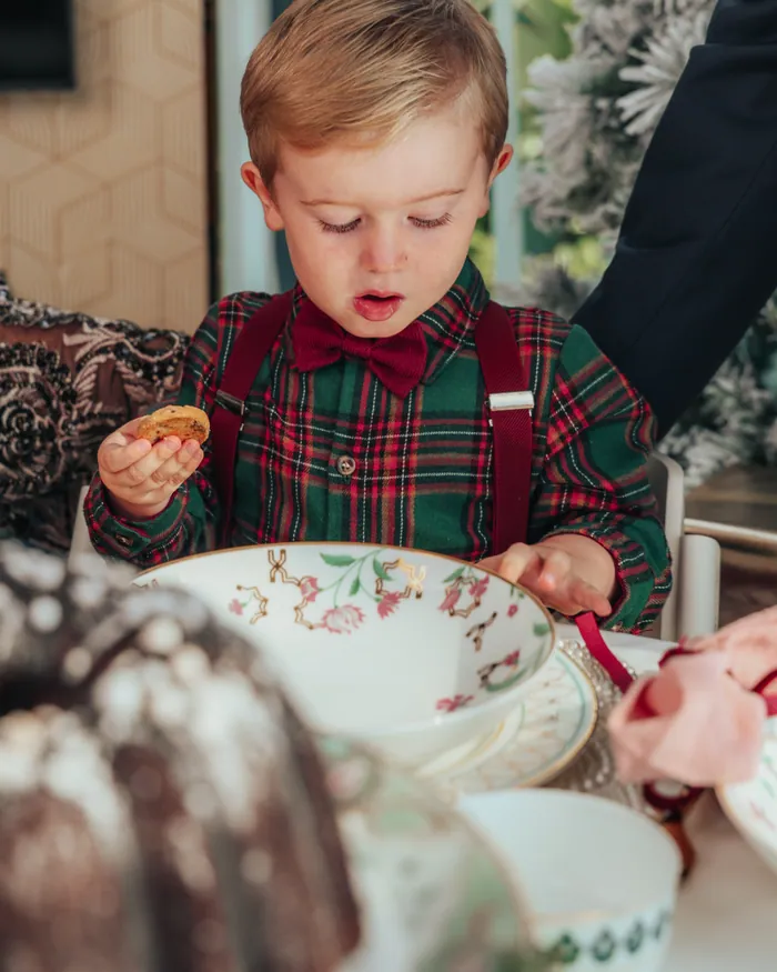 A small boy in a tartan shirt, red braces and bow tie at the Christmas table