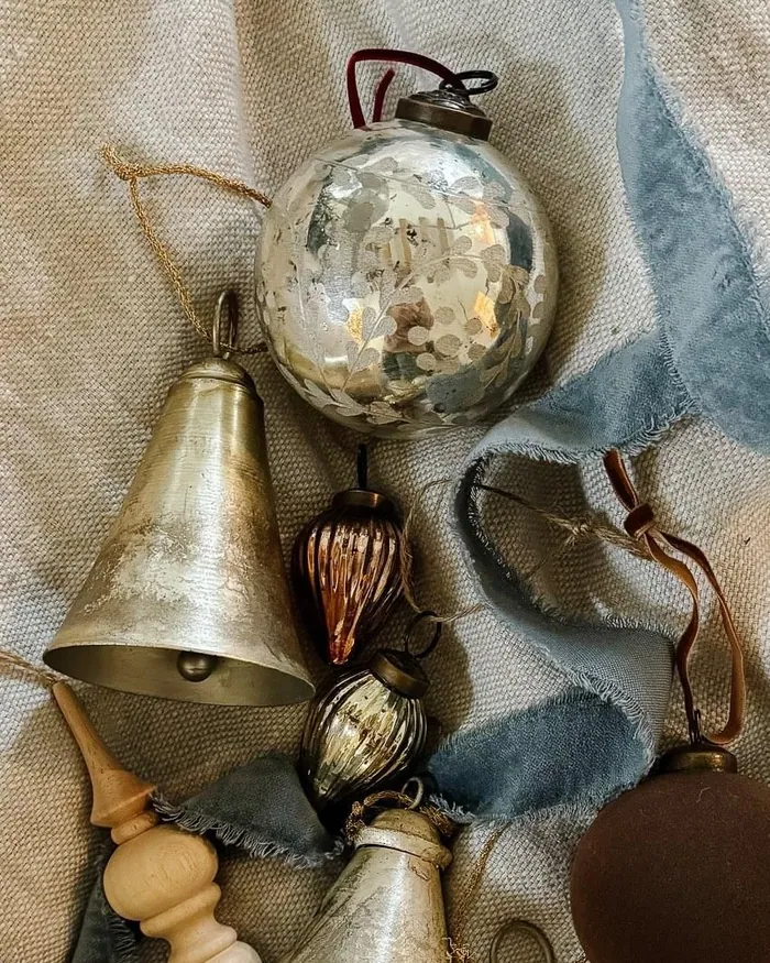 Brass bells, glass baubles and blue ribbon laid out on linen, ready to be wired onto a wreath