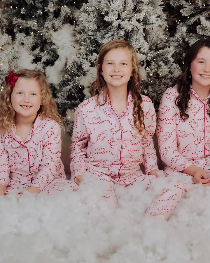 Three sisters in pink pyjamas sitting together in the snow