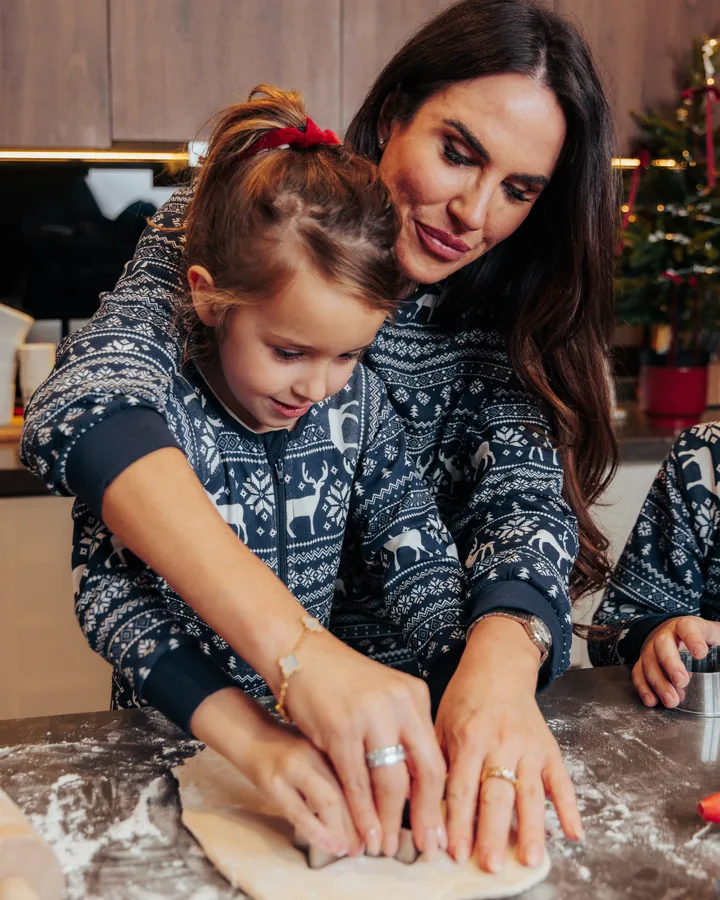 A mother and daughter in matching navy jumpers pressing dough on a floured counter
