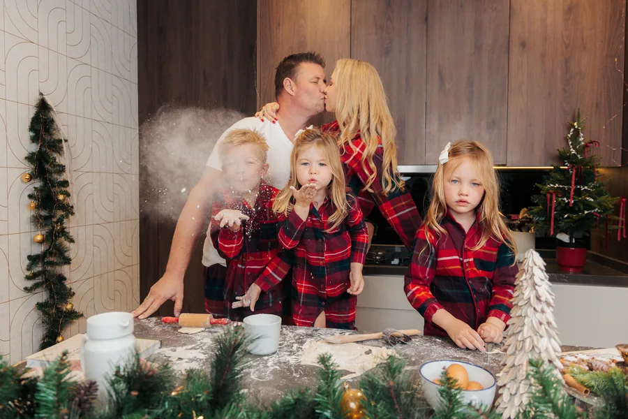 A family in tartan pyjamas at the counter, a cloud of flour in the air
