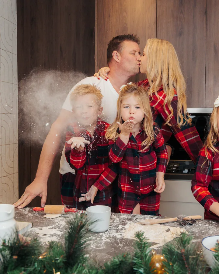 A family in tartan pyjamas at the counter, a cloud of flour in the air