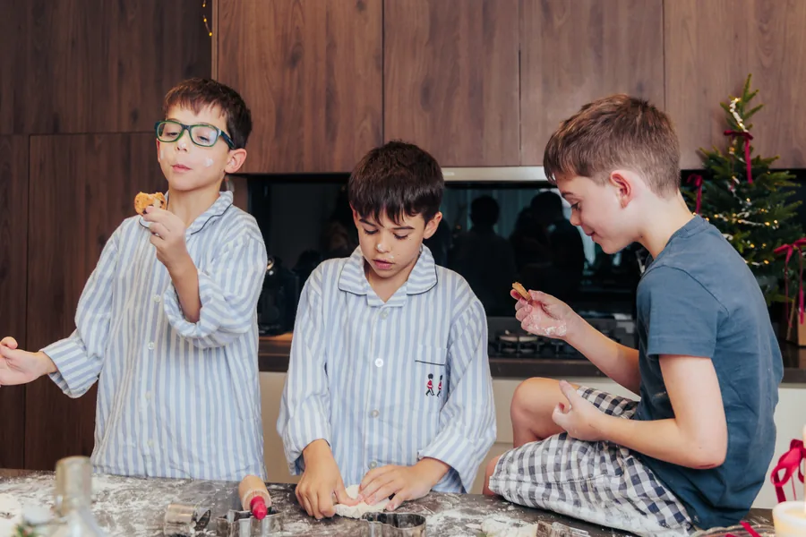 Three boys in striped pyjamas at the counter, one of them blowing flour