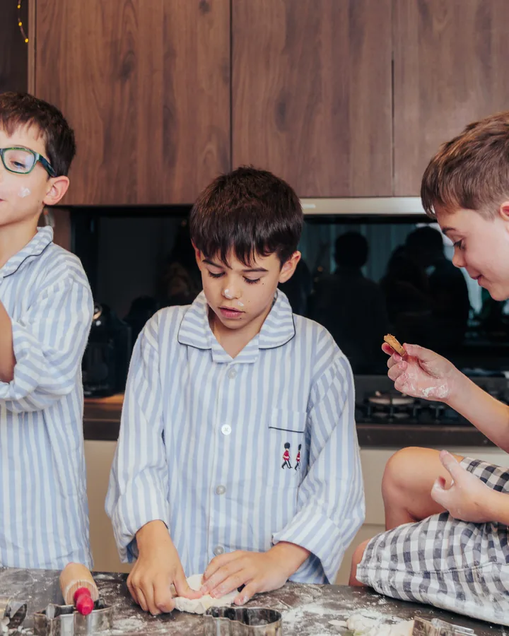 Three boys in striped pyjamas at the counter, one of them blowing flour