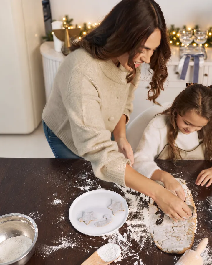 A mother and daughter rolling biscuit dough together in the Christmas Kitchen