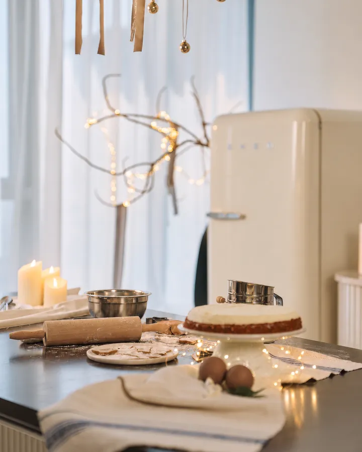 The Christmas Kitchen: a cream fridge, candles and a cake on a floury table