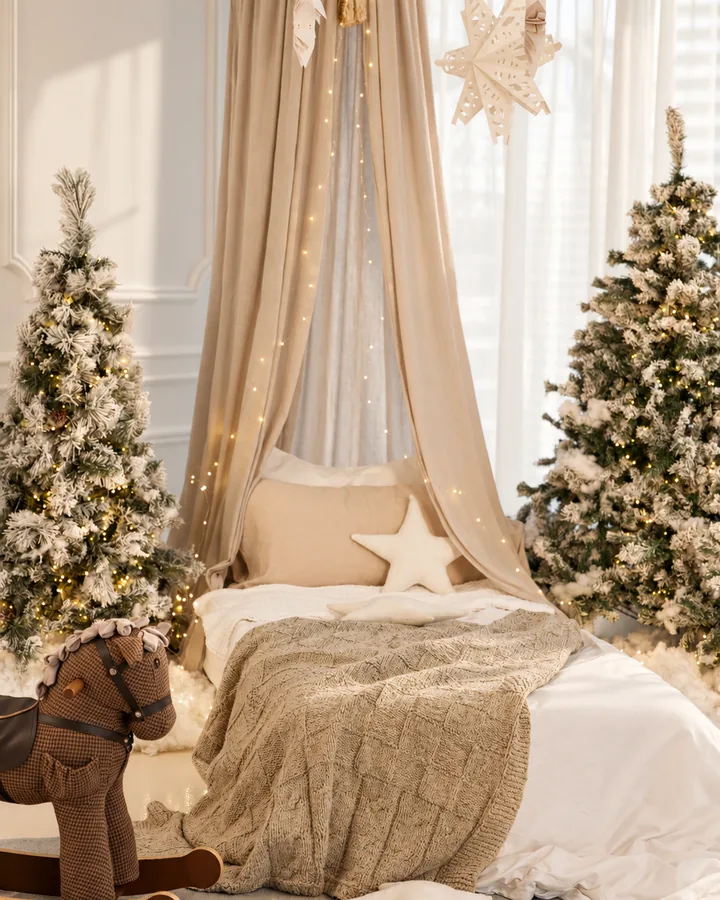 A canopy bed between two snowy trees in Christmas Morning, paper stars and fairy lights above