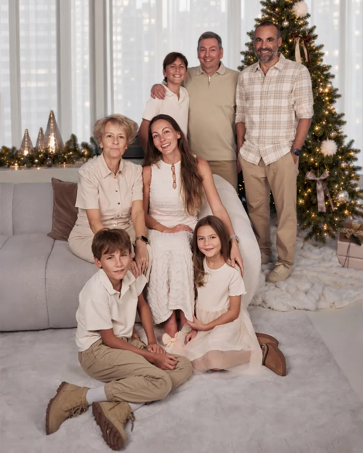 Three generations of one family in cream and beige, gathered by the Christmas tree in the Christmas Room